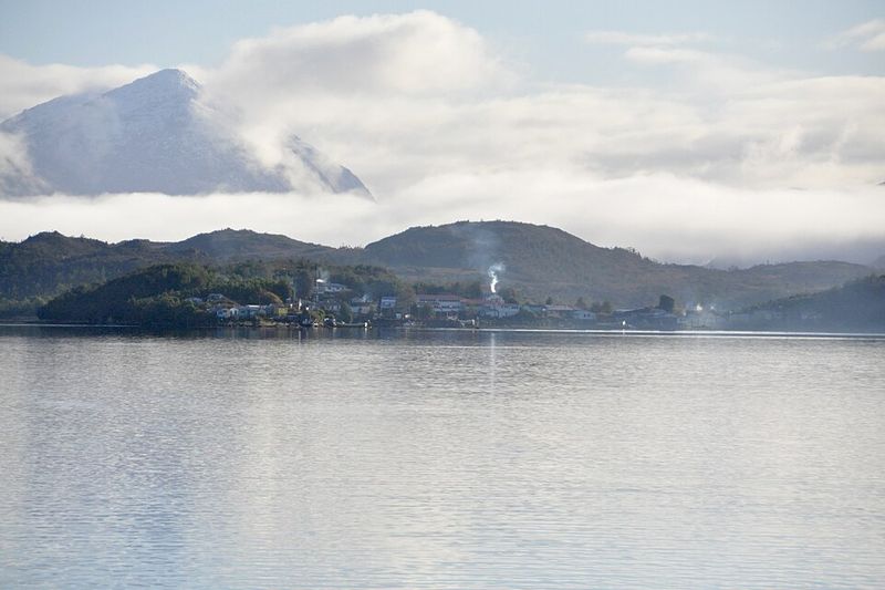 Puerto Edén al borde del agua, con montañas y nubes al fondo